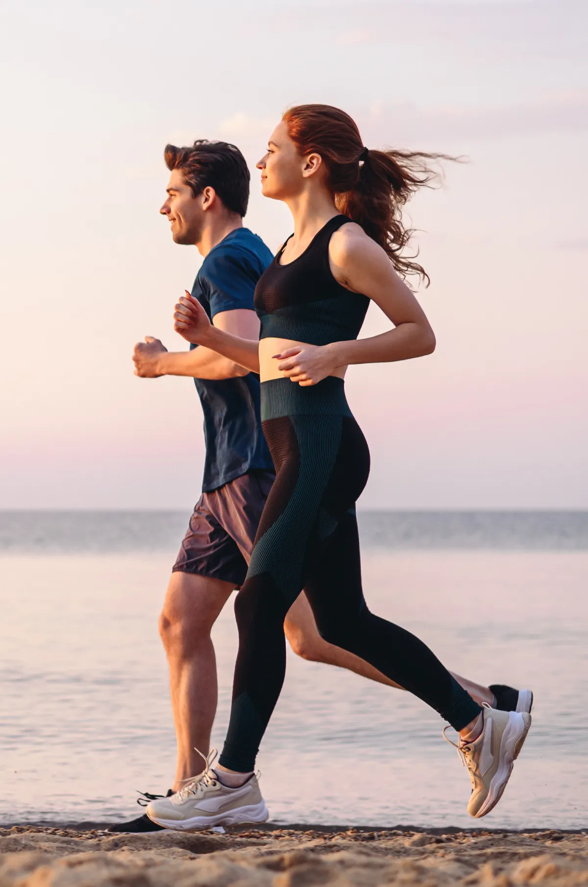 Couple running on the beach at sunset, embodying a healthy lifestyle and wellness in Provo, UT.