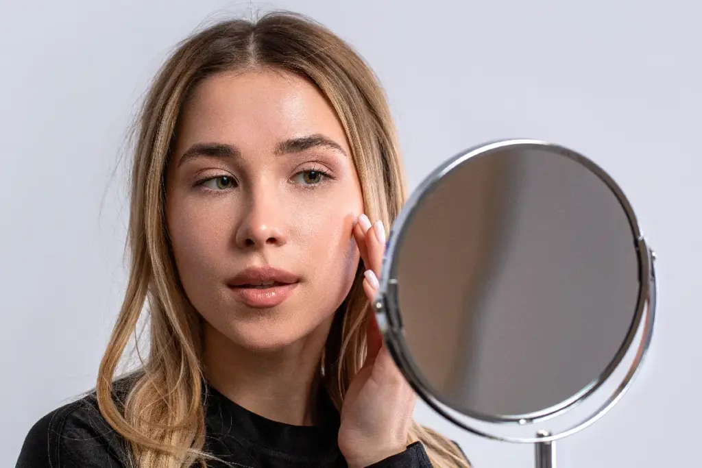 Young woman checking skin texture and early aging concerns before collagen support treatment.