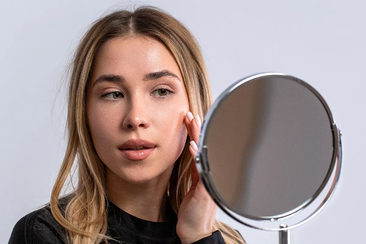 Young woman checking skin texture and early aging concerns before collagen support treatment.